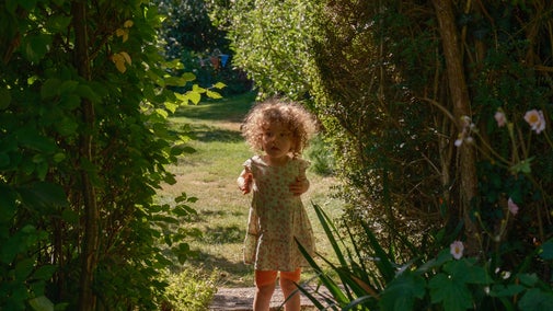 A young visitor stands under a hedge arch at Paycocke's House, Essex